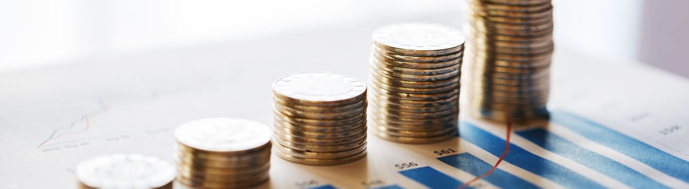 Aufsteigende Münzstapel auf einem Finanzdiagramm