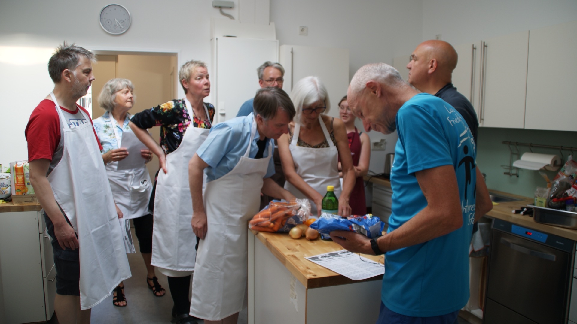 Gruppe beim Kochkurs in Küche mit Schürzen