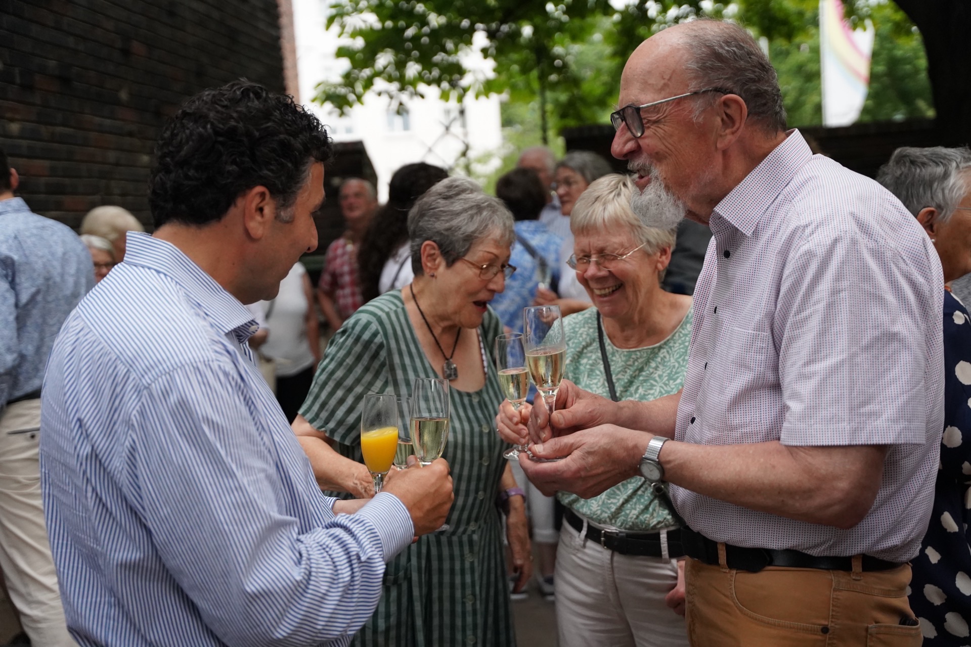 Menschen stoßen bei Gartenfeier mit Sekt an