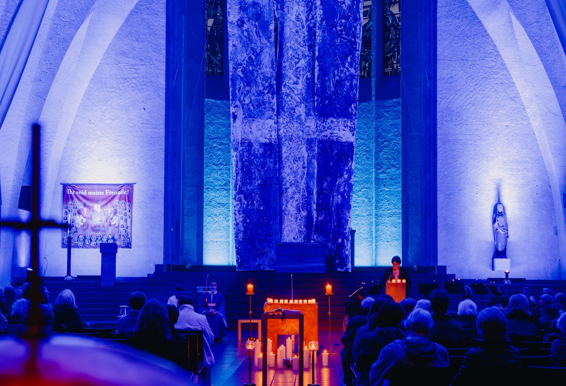 Gottesdienst mit Kerzen und blau beleuchtetem Altarraum